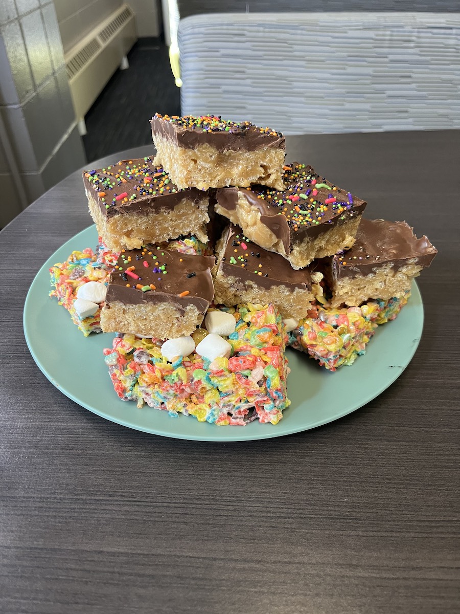 A mixture of scotcheroos and Fruity Pebbles Rice Krispies aligned in a stack on a plate.