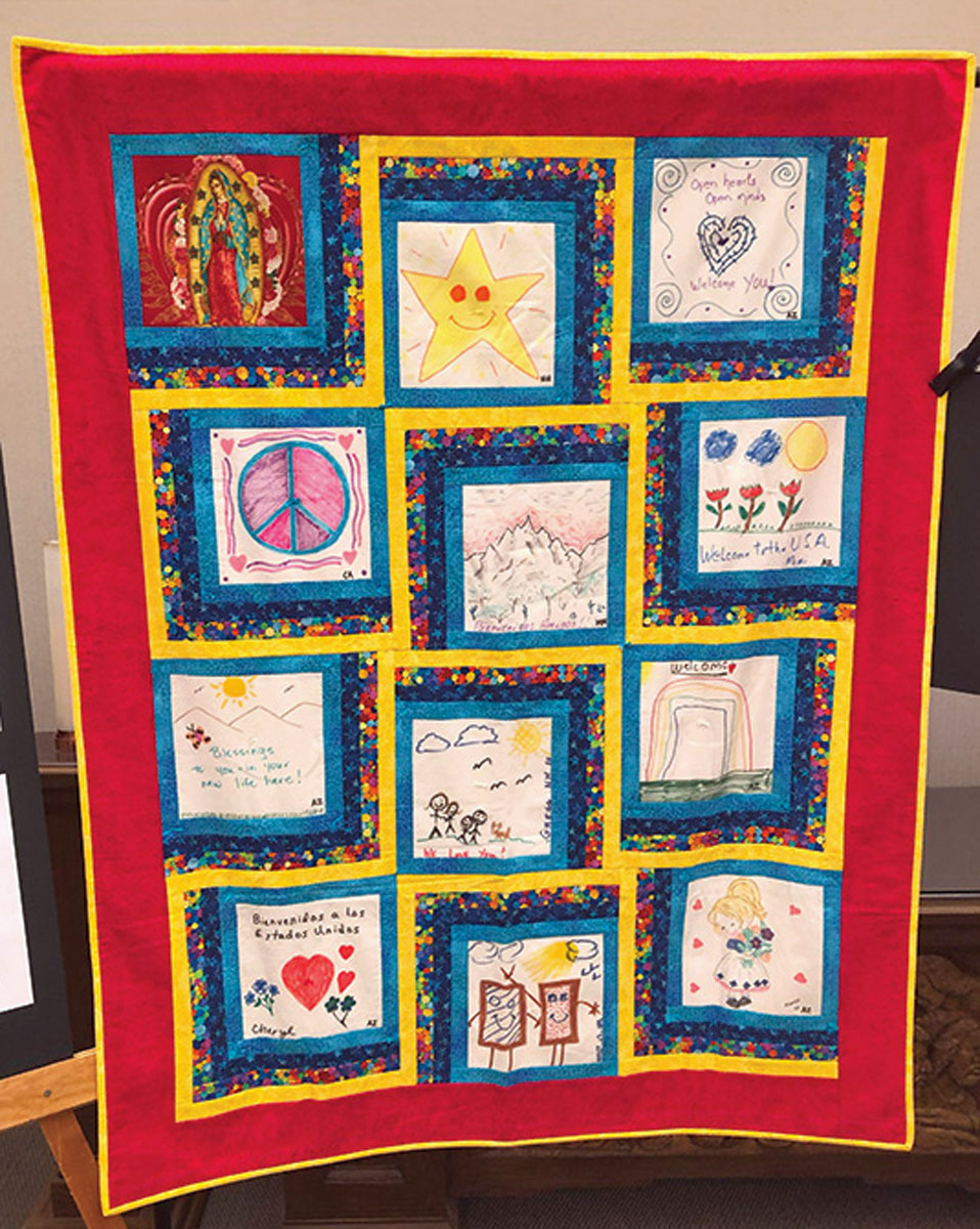 Fabric drawings from the Patagonia community. Colored fabric acts as symbols to welcome migrant families. An example includes the use of turquoise which “represents the sky that covers both their country of origin and their new home.” Image of “Our Lady of Guadalupe” seen in top left corner.