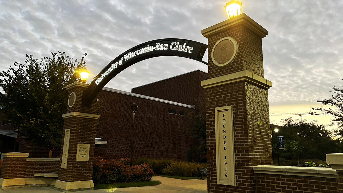 UW-Eau Claire’s arch lit up beneath the clouds between Zorn Arena and Hibbard Humanities Hall.