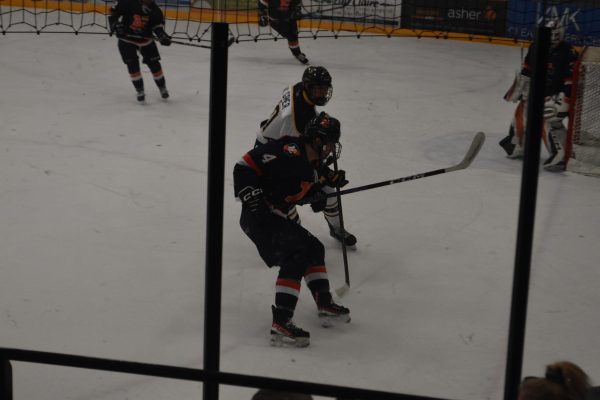 Blugold and Northland player going after a puck near the corner.